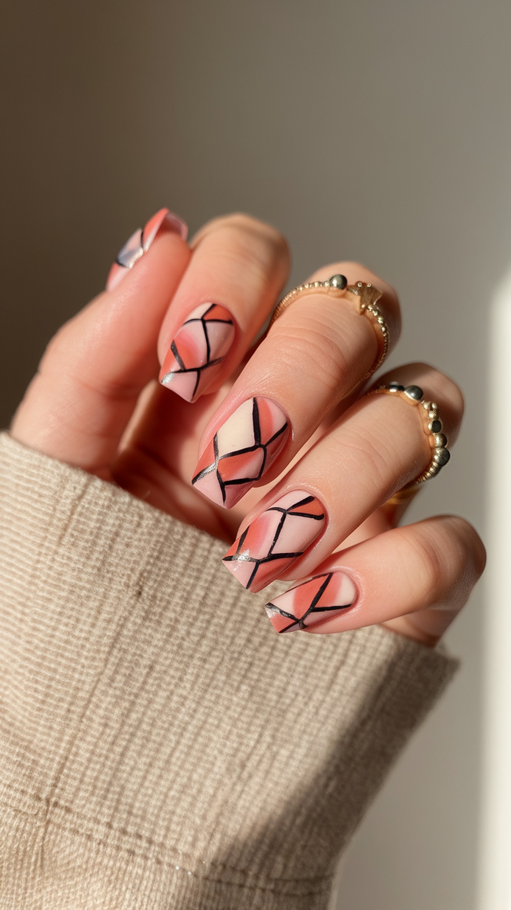 Nail design featuring geometric patterns in sunset colors with black lines.