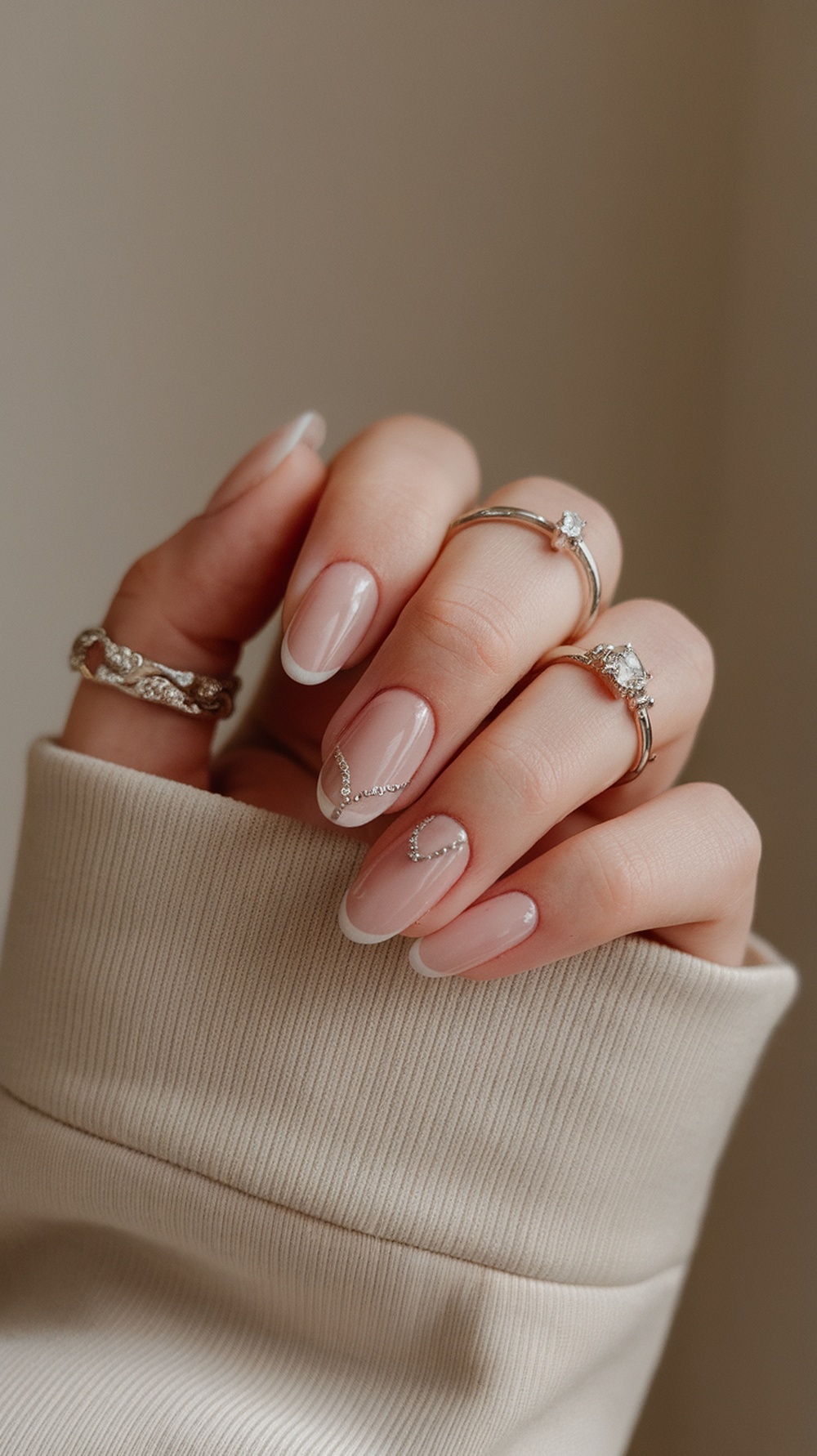 Nails with a pink base and glitter fade, adorned with rings