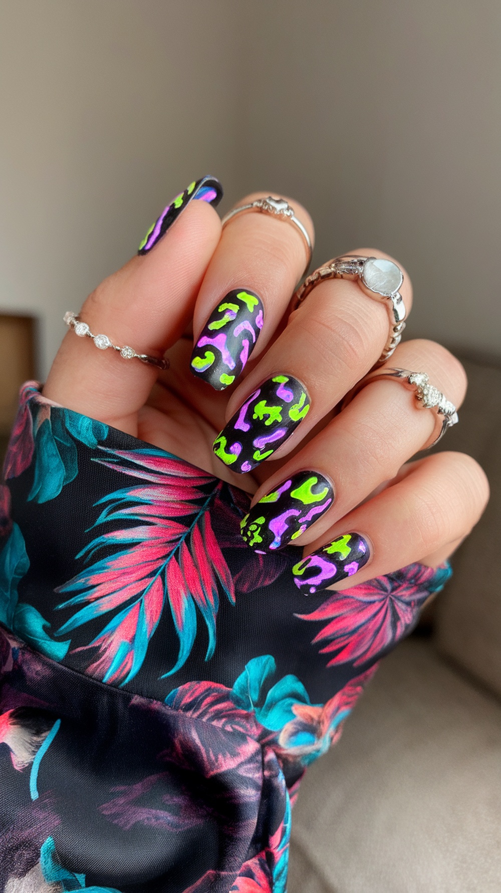 Close-up of neon animal print nails with vibrant colors on a dark background.