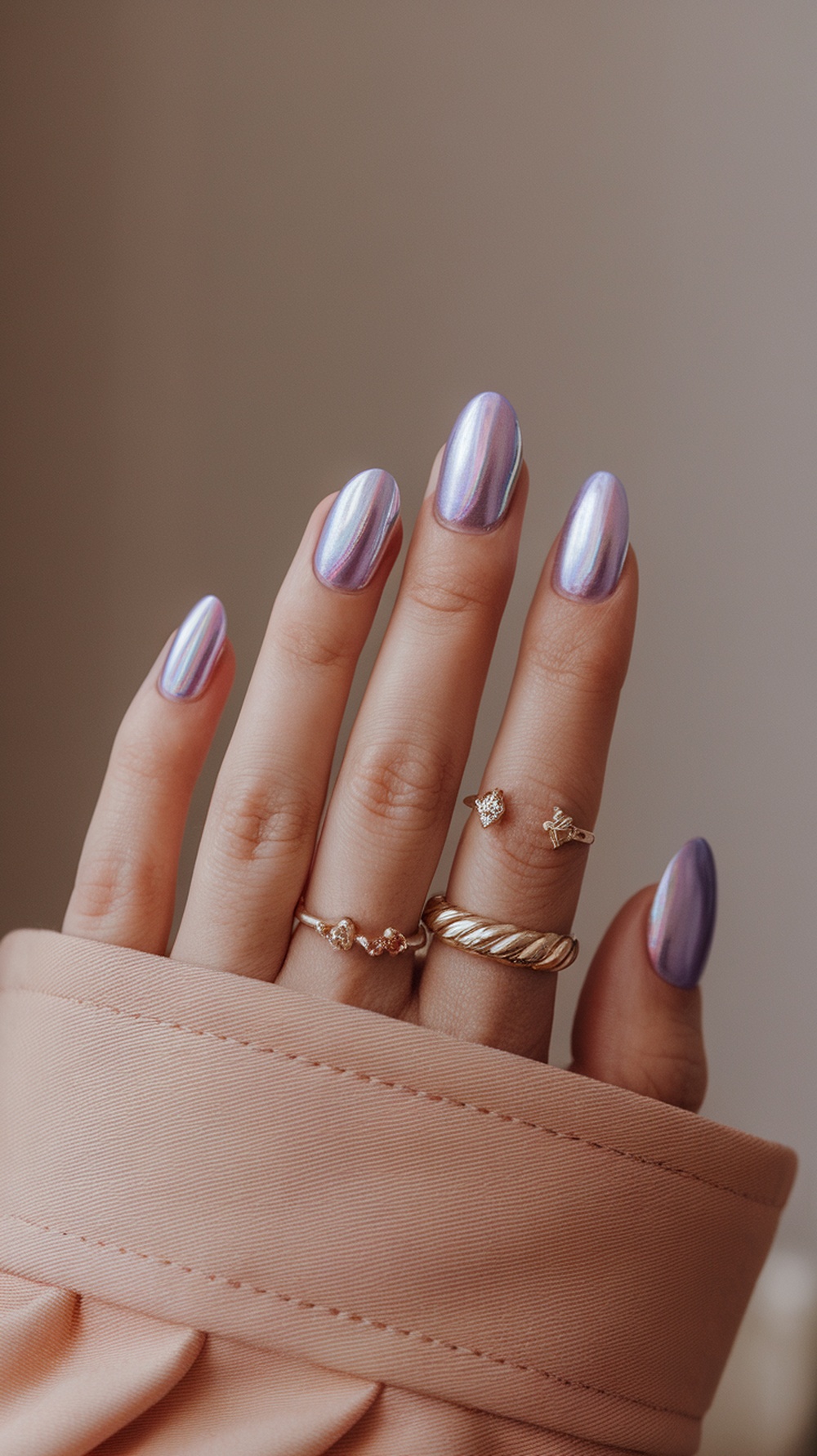 A close-up of hands with cotton candy chrome nails, showcasing a glossy finish and rings.