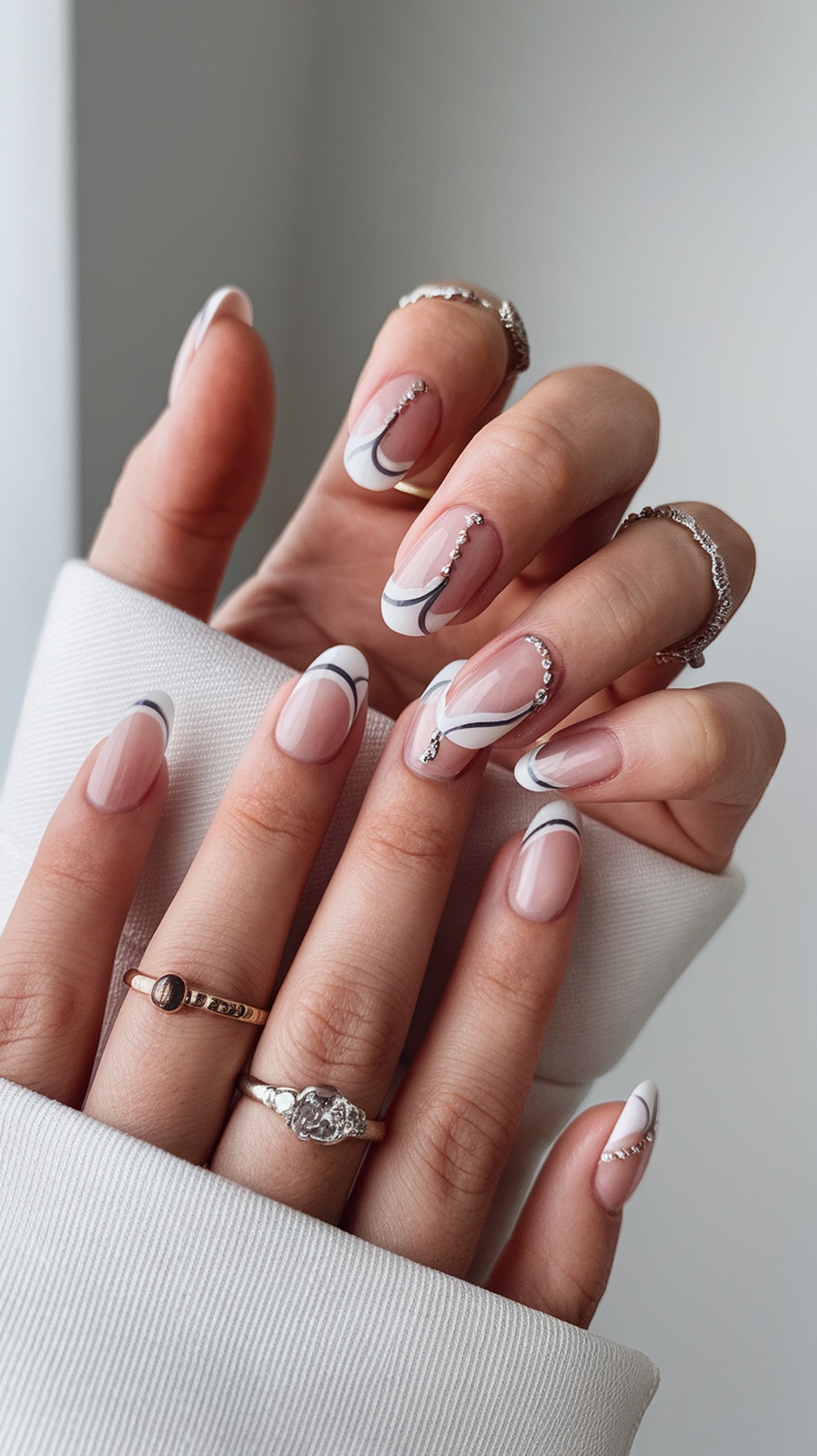 Minimalist summer nail design featuring nude tones with white and black lines and small gems