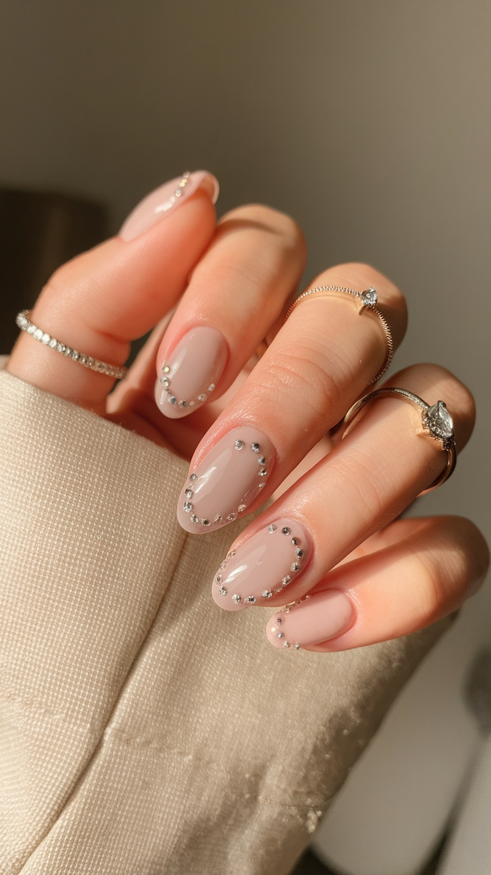 Close-up of minimalist nail design with rhinestone dots on nude nails