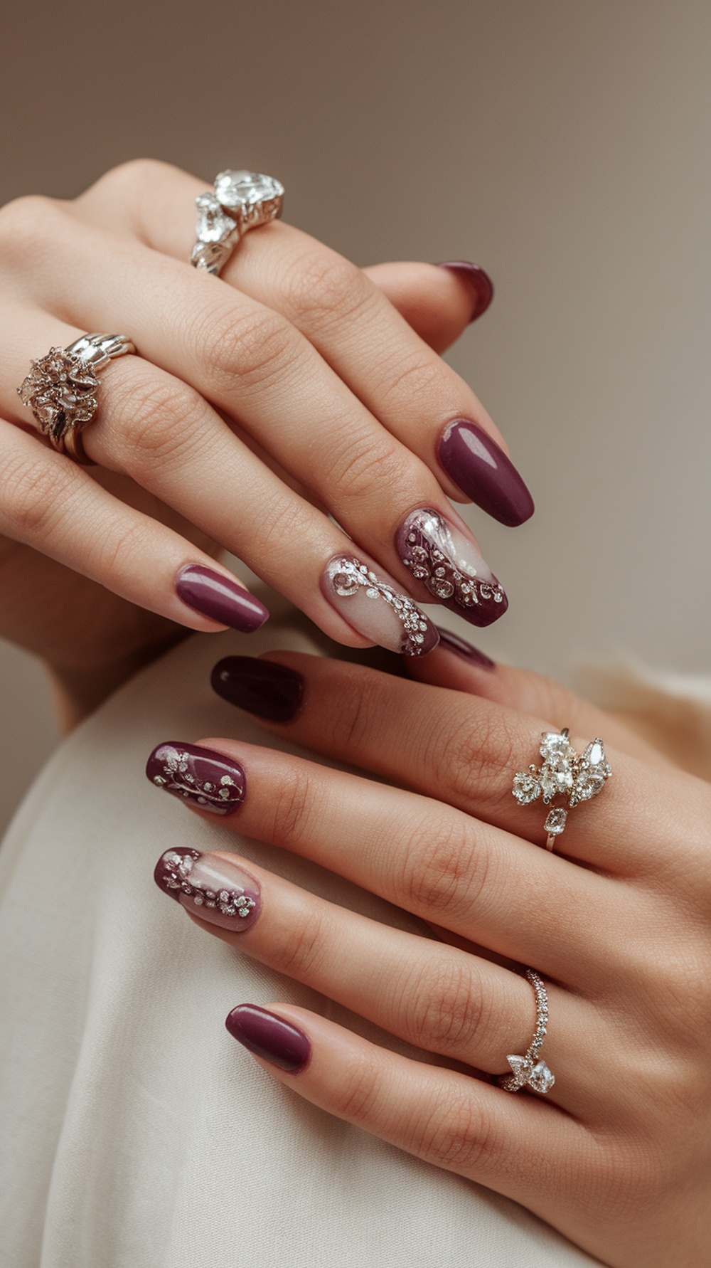 Close-up of hands with plum nails featuring intricate designs and rings