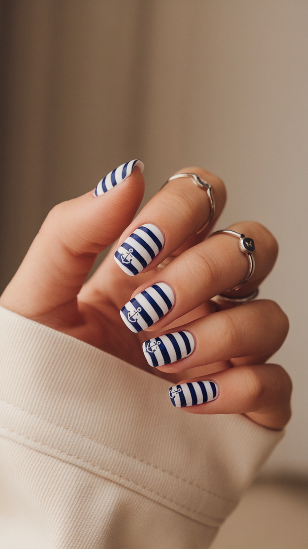 Nails painted with nautical stripes and anchors, showcasing a summer theme.