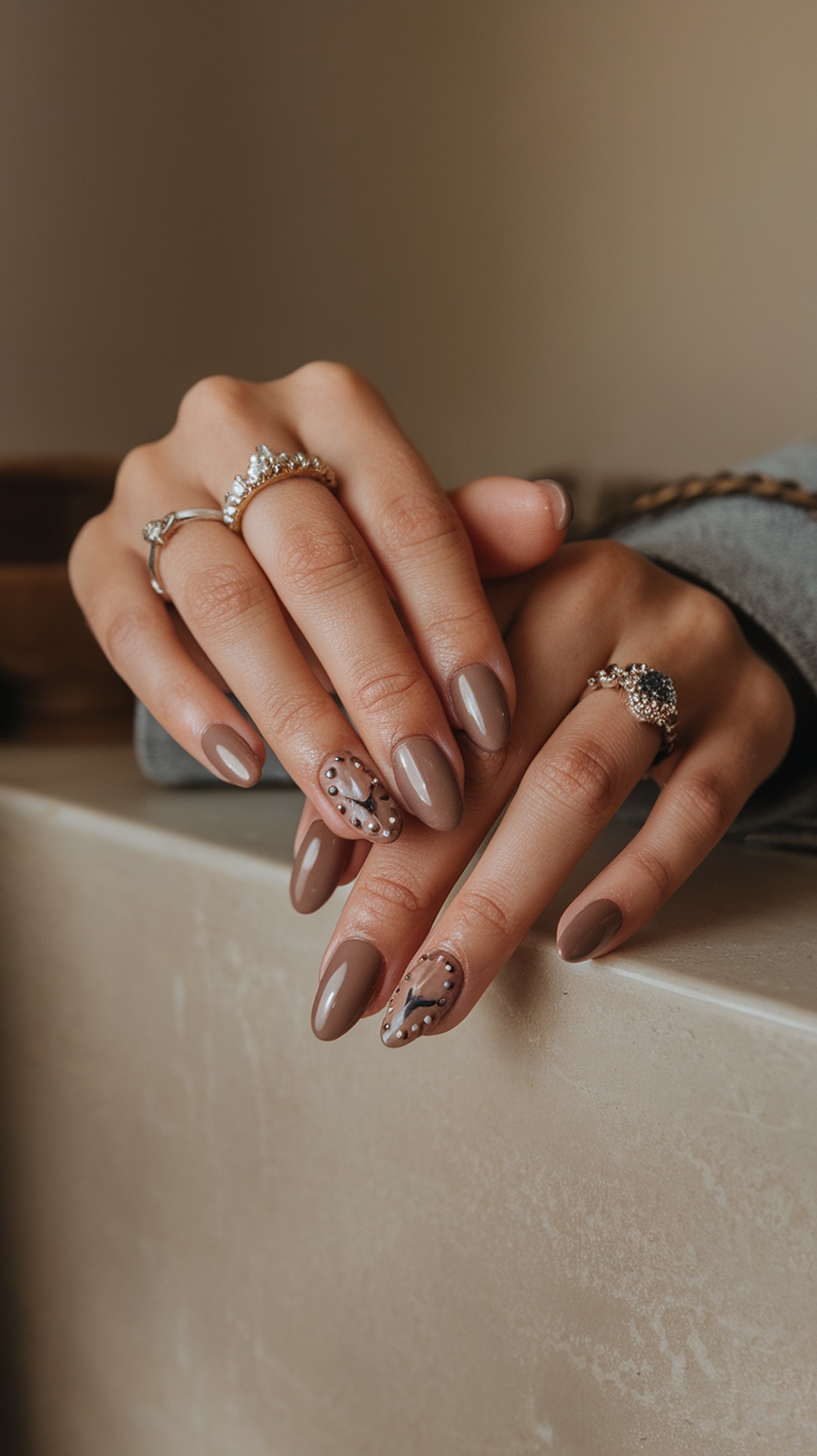 Nude brown nails with studded details, showcasing a stylish manicure.