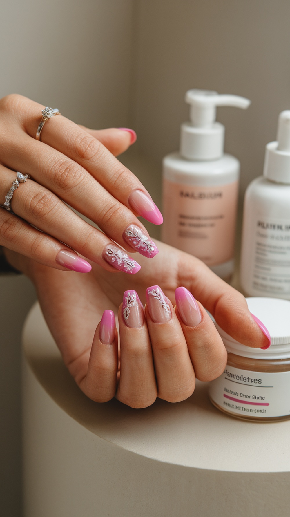 Nude pink nails with delicate designs, surrounded by skincare products.