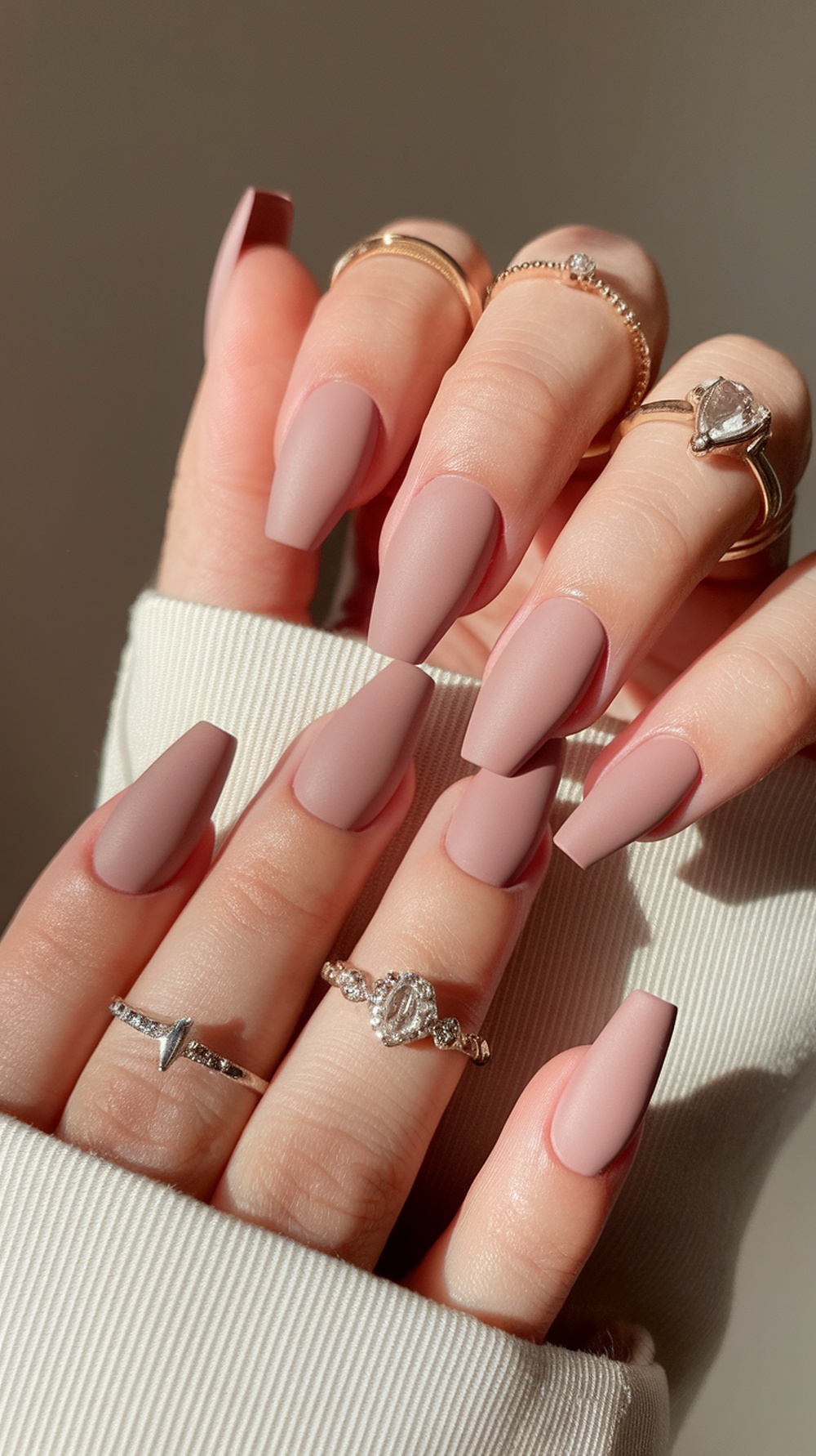 Close-up of hands with nude pink matte nails and rings