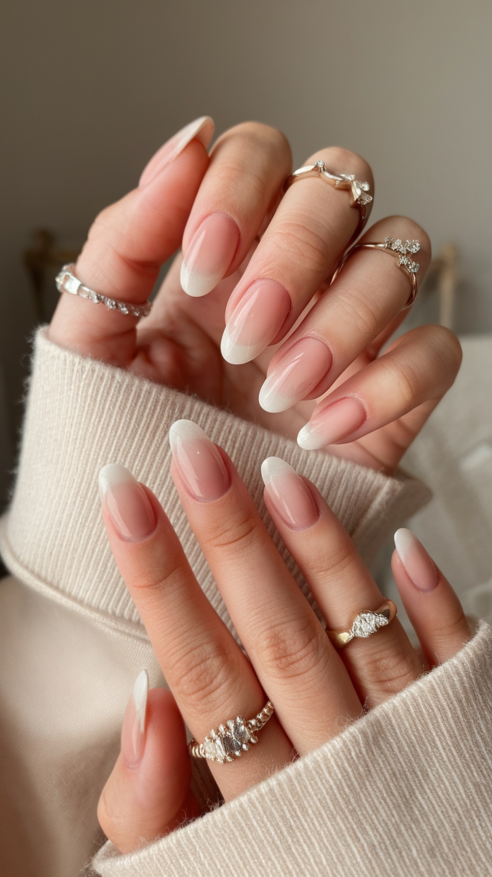 Close-up of hands with nude pink ombre nails and delicate rings