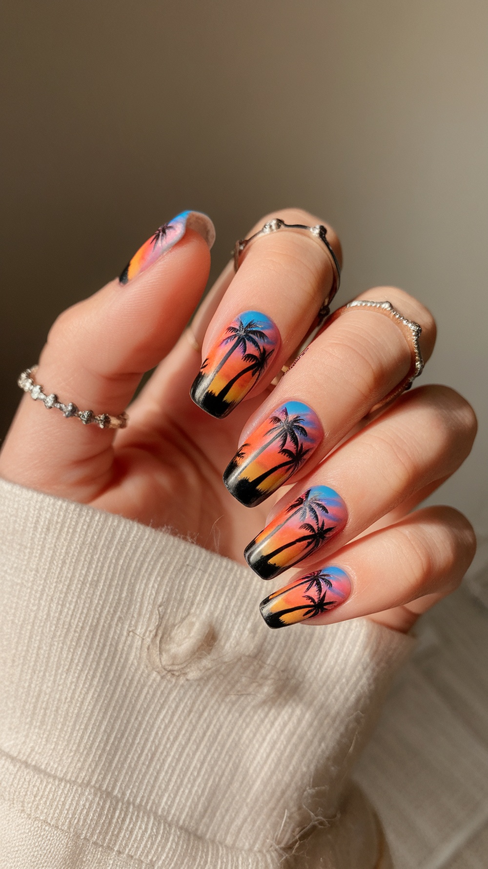 Nail design featuring sunset colors with palm tree silhouettes