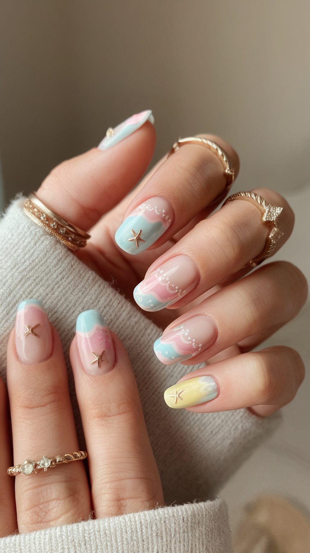 Pastel beach-themed nails with wavy patterns and starfish embellishments.