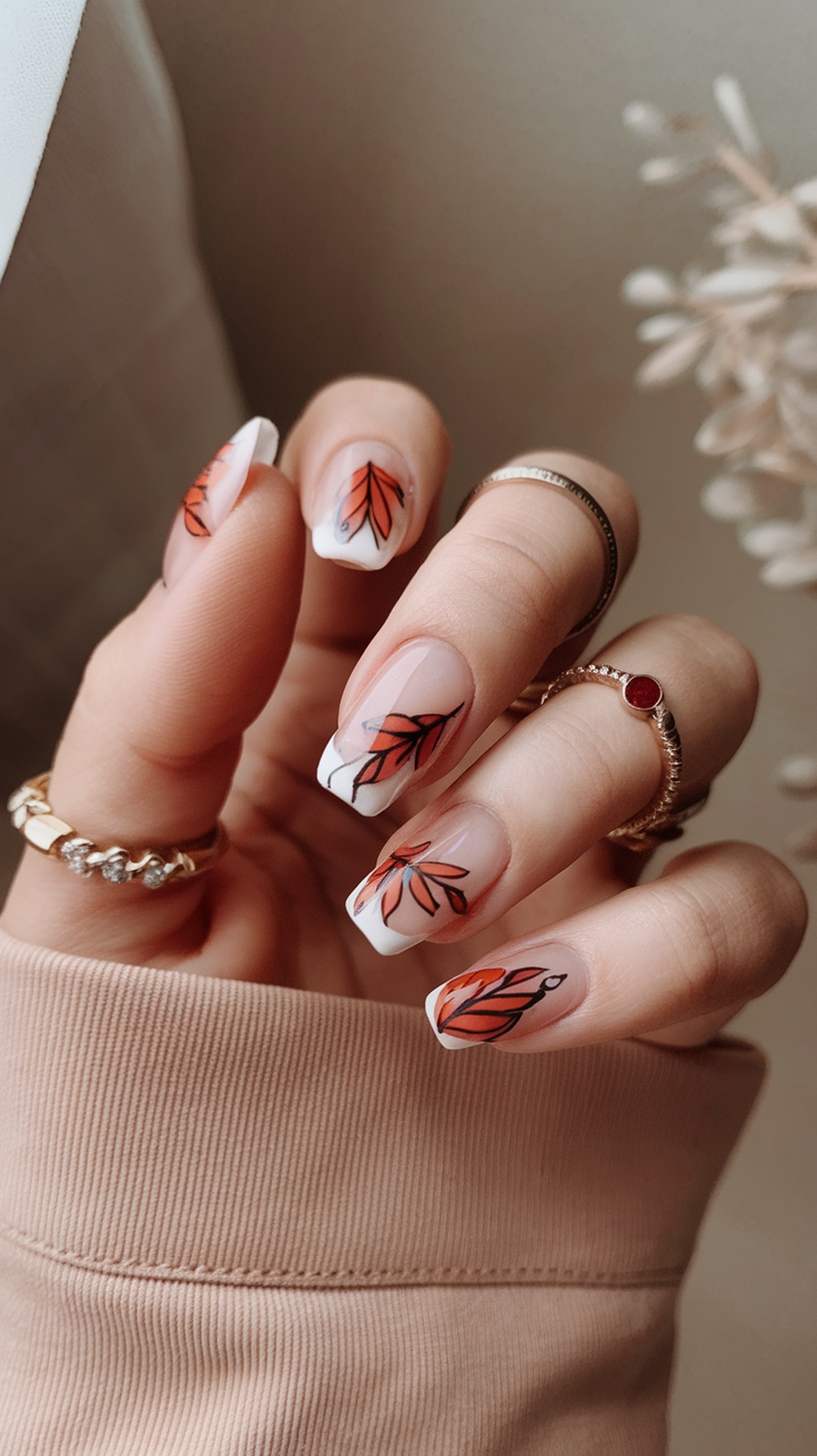 Nail design featuring fall leaves in orange and black on a clear base.