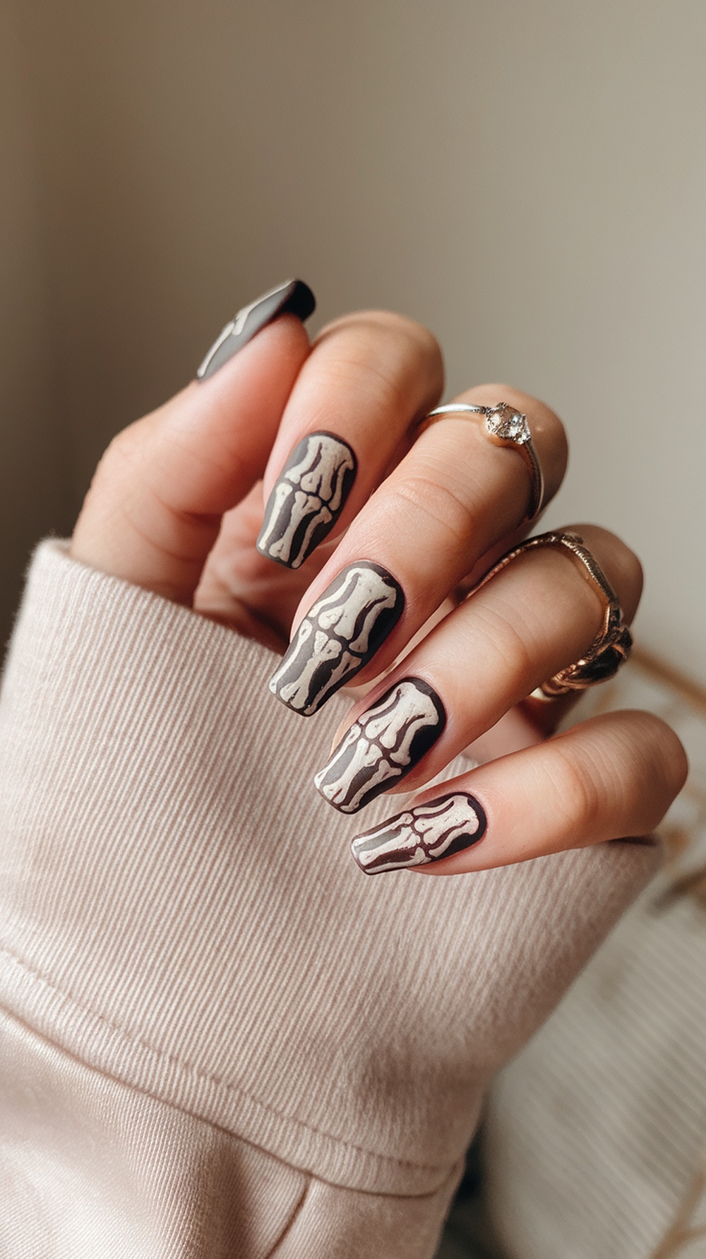 Nails painted with skeleton hand design, featuring a dark base and white bone patterns.