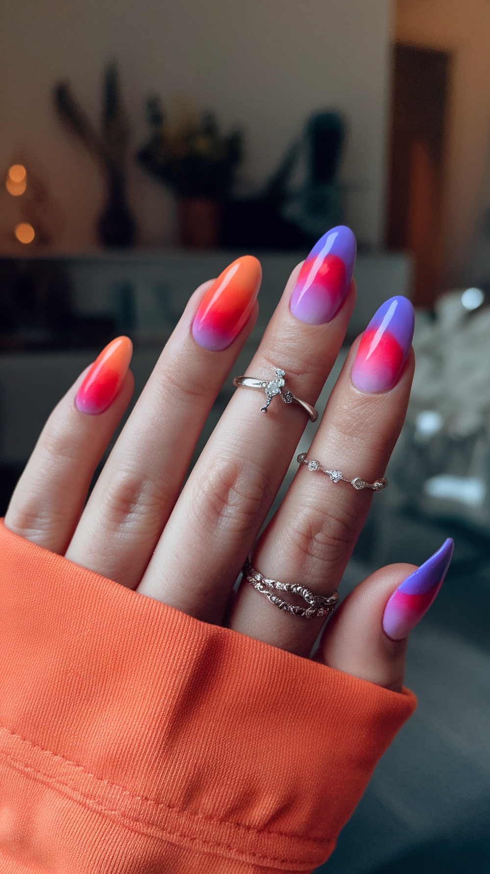 Nails with a tropical sunset gradient design featuring orange and purple colors.