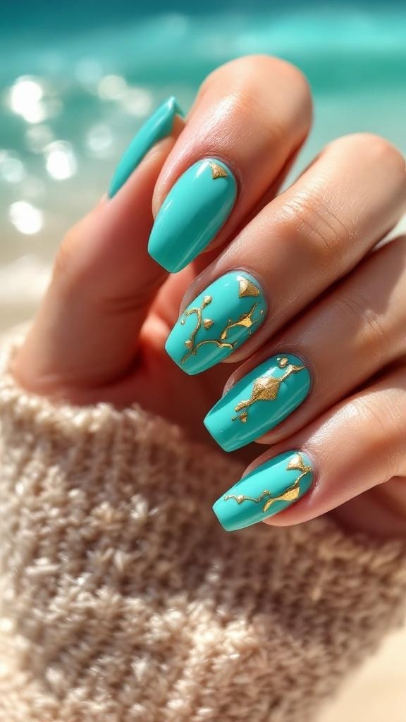 A hand with turquoise nails featuring gold accents, resting on a sandy surface.