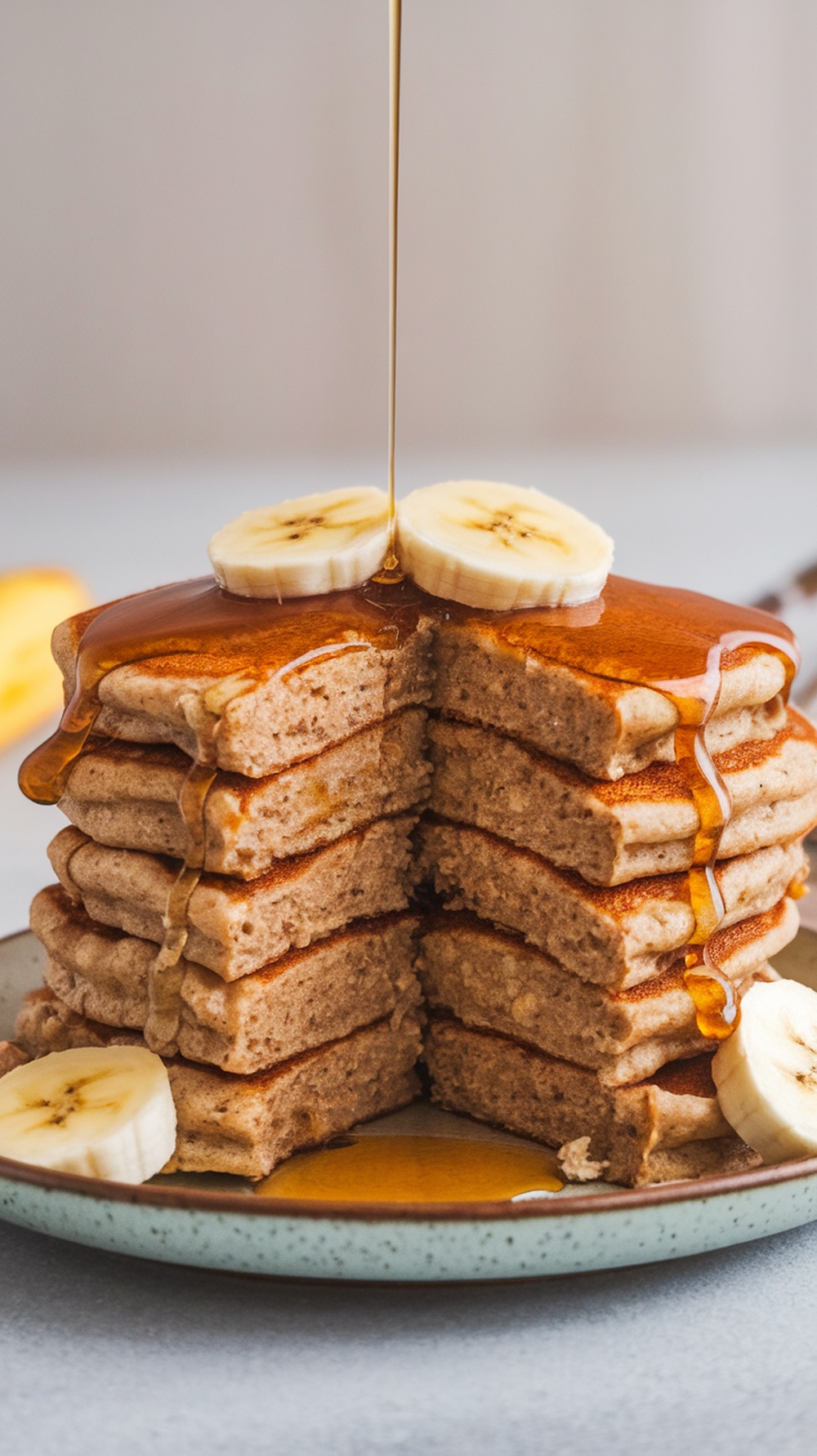 Stack of banana oatmeal pancakes with syrup and banana slices