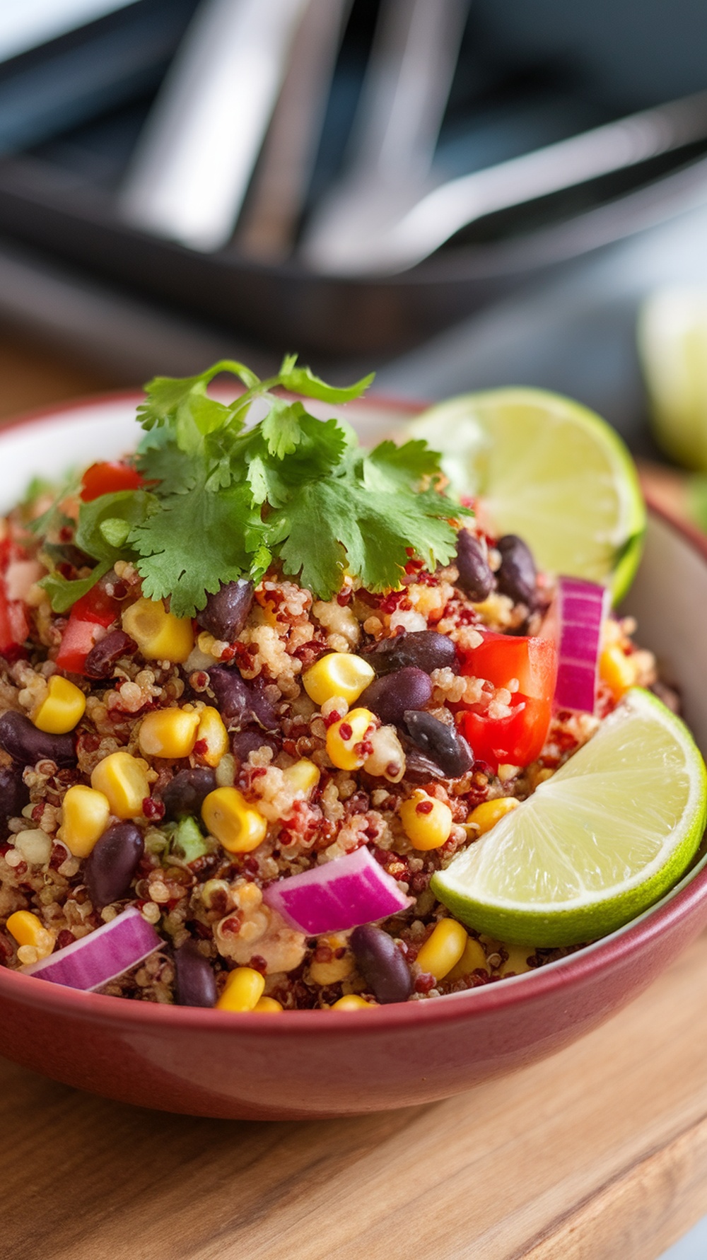 A colorful quinoa and black bean salad with corn, diced red bell pepper, and lime wedges, garnished with cilantro.