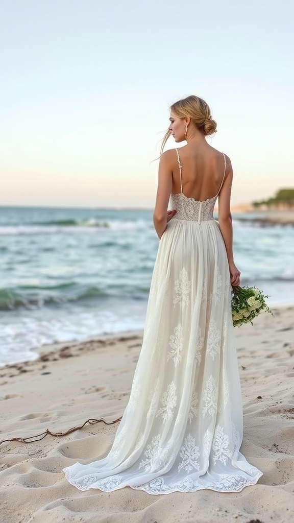 A woman in an off-white lace dress standing on the beach, with the ocean waves in the background.