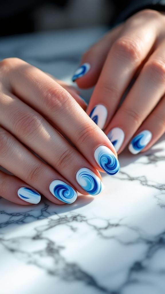 Close-up of hands with blue and white swirl nail design on a marble surface