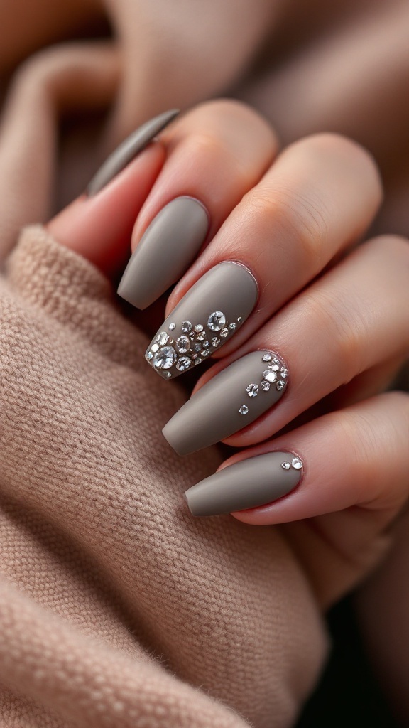 Close-up of textured matte nails with rhinestones on a hand.