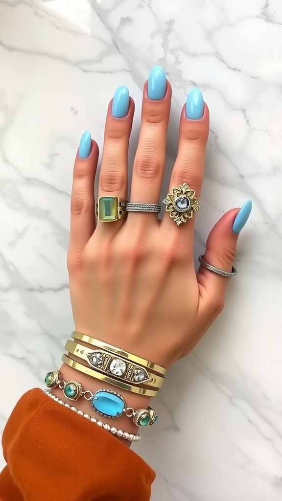 A hand with light blue almond nails, adorned with various rings and bracelets.