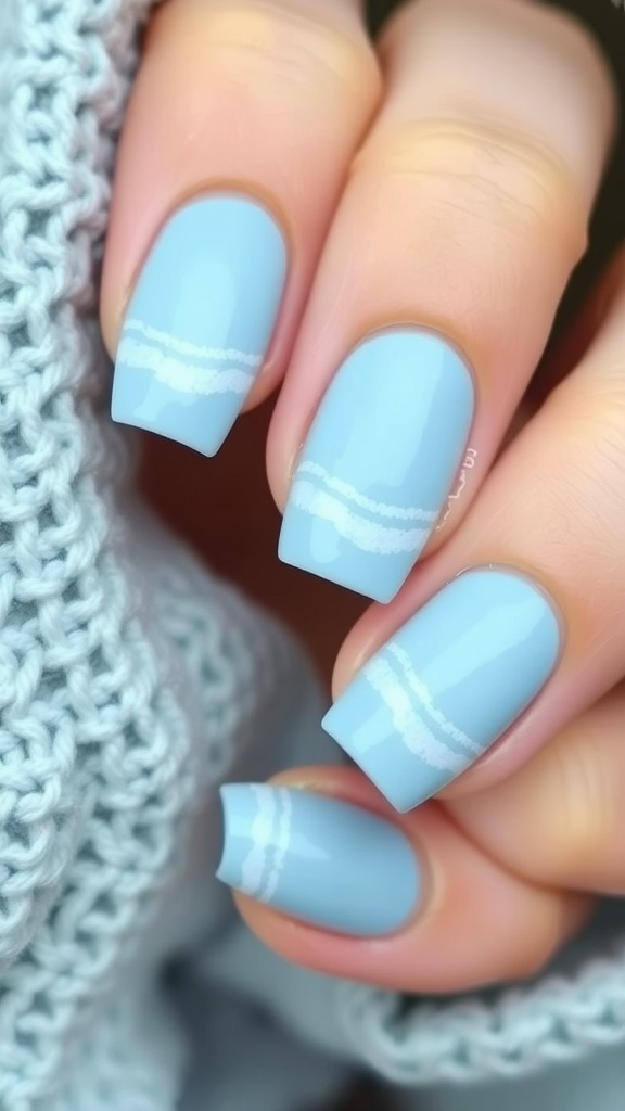 A close-up of light blue nails with white wave designs against a knitted background.