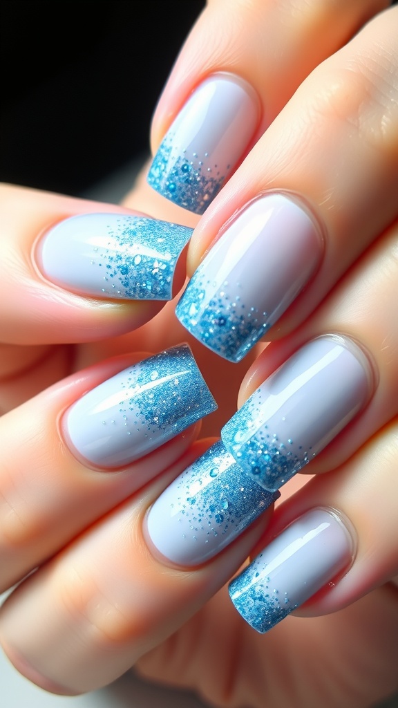 Nails featuring a light blue base with glittery blue tips, showcasing a stylish ombre effect.