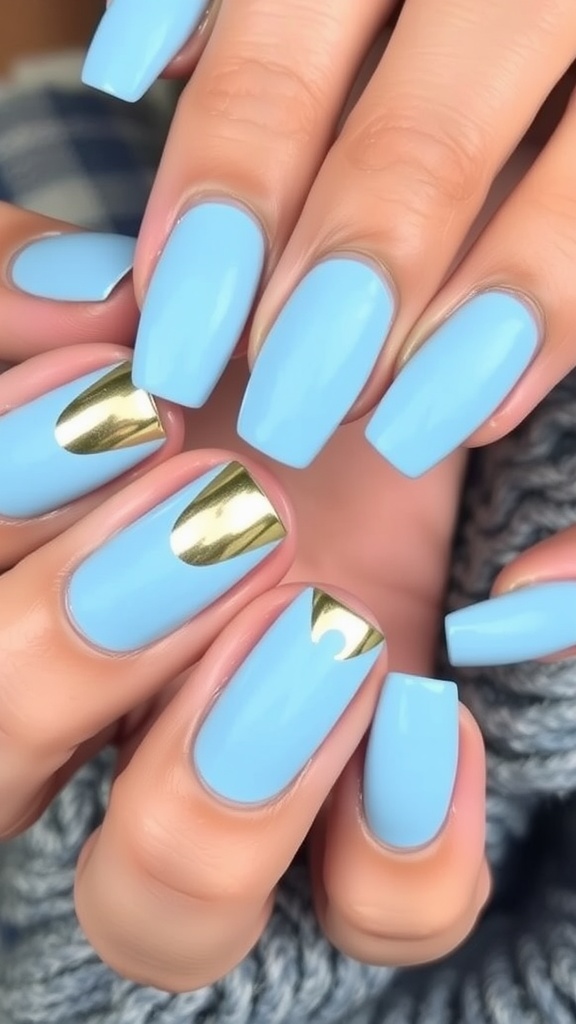 Light blue nails with bold metallic gold tips, featuring creative shapes and angles.