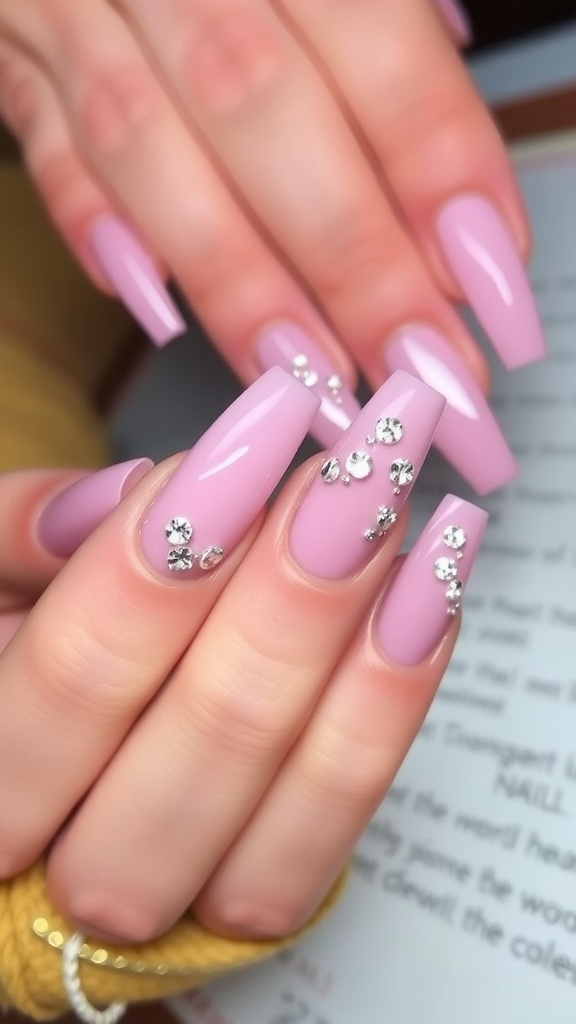 Close-up of long pink acrylic nails with crystal embellishments
