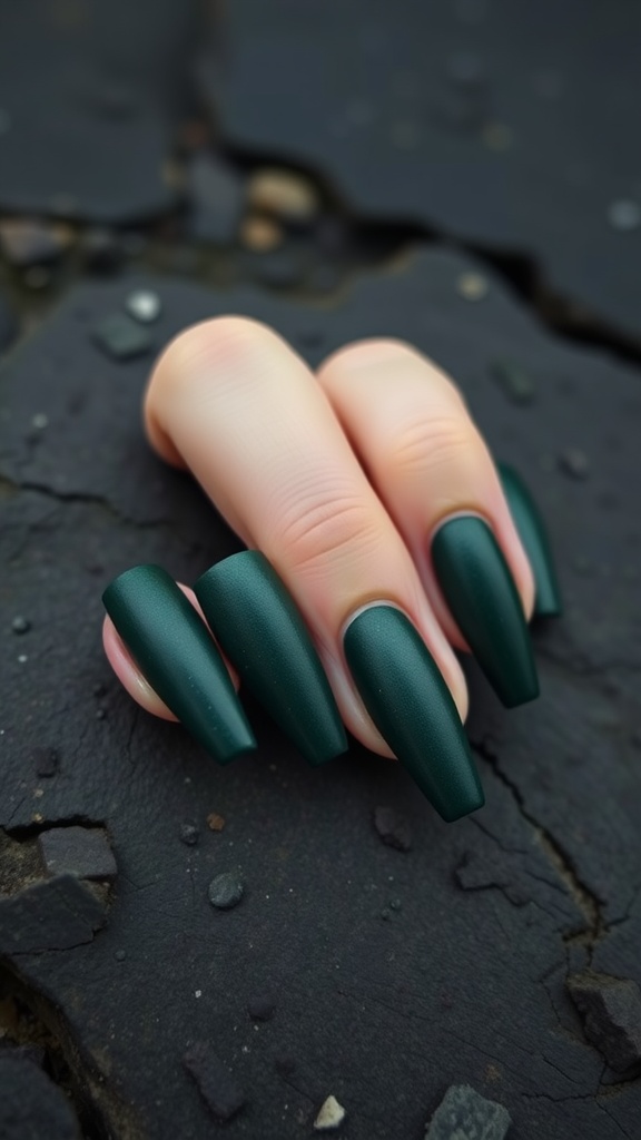 A close-up of dark green coffin nails with a matte texture, resting on a textured surface.