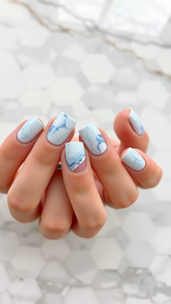 Close-up of light blue marble nails with French tips on a hexagonal tile background.