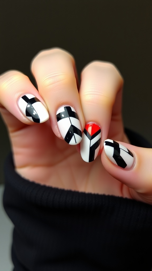 A hand showing acrylic nails with bold geometric patterns in black, white, and a touch of red.