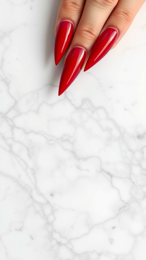 Glossy cherry red stiletto nails on a marble background