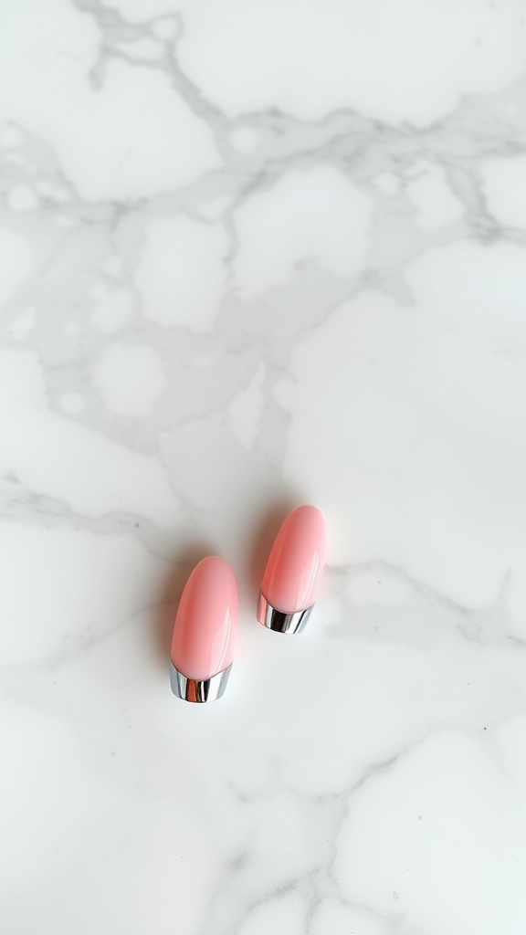 Short nails with a glossy light pink base and metallic tips on a marble surface.