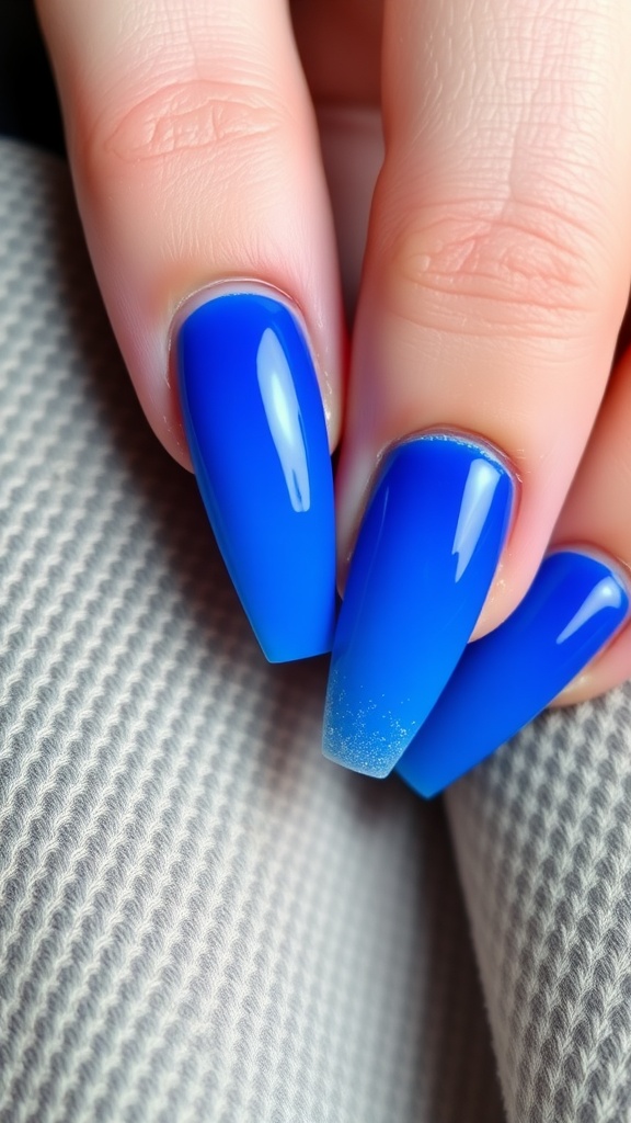 Close-up of gradient royal blue acrylic nails with glitter tips