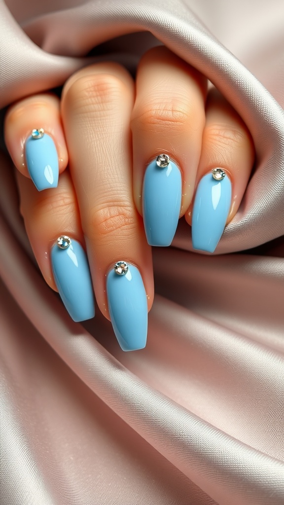 Light blue chrome nails with rhinestones, displayed elegantly on a silky background.
