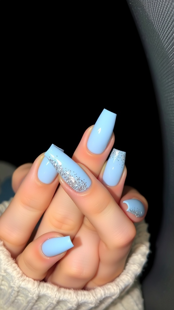 Close-up of light blue acrylic nails with a glitter fade design.