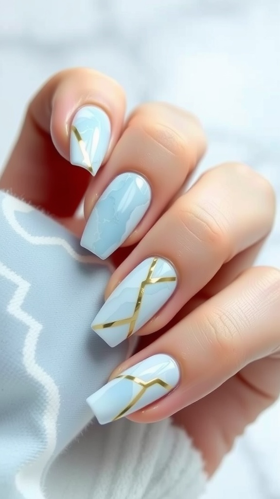 A close-up of light blue marble nails with metallic gold stripes.