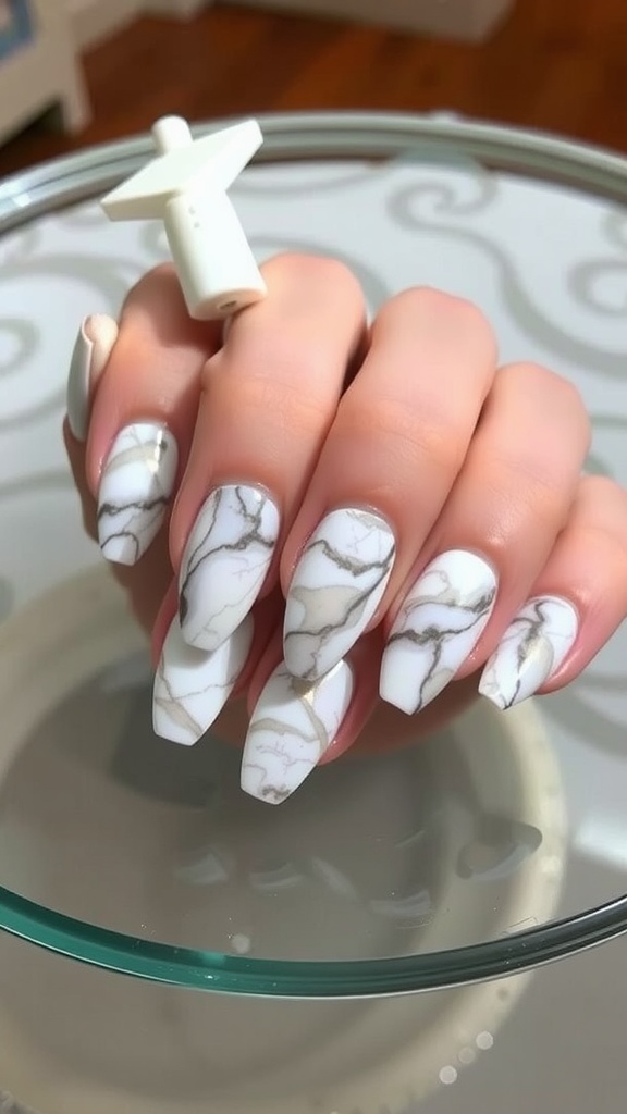 Close-up of almond-shaped nails with a marble effect design in white and beige.