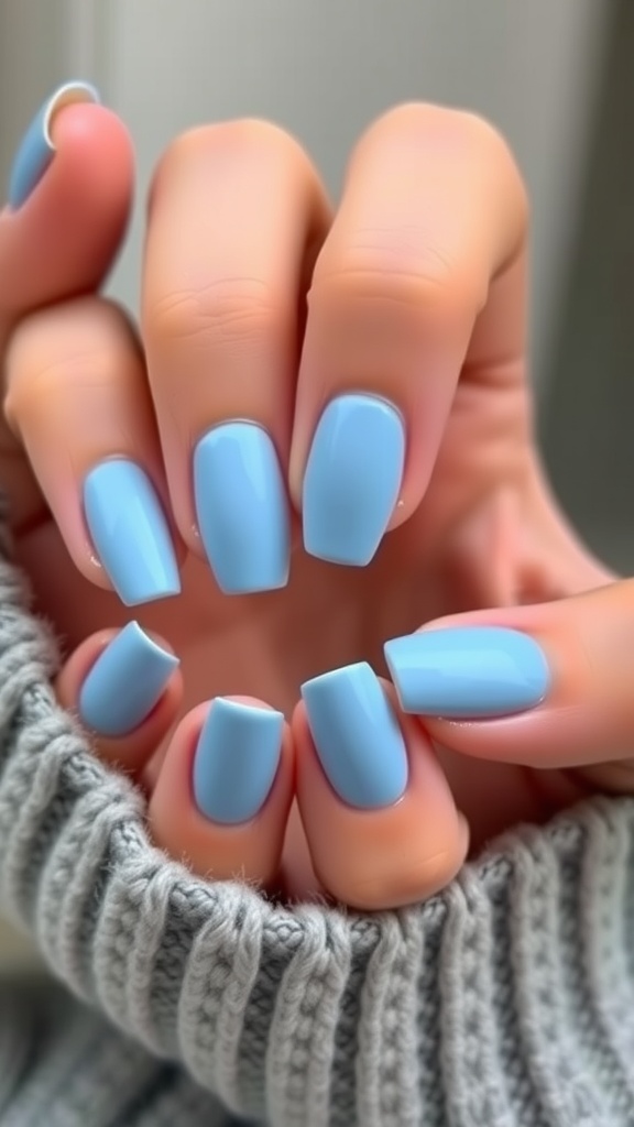 Light blue matte finish nails displayed elegantly against a gray knit sweater.