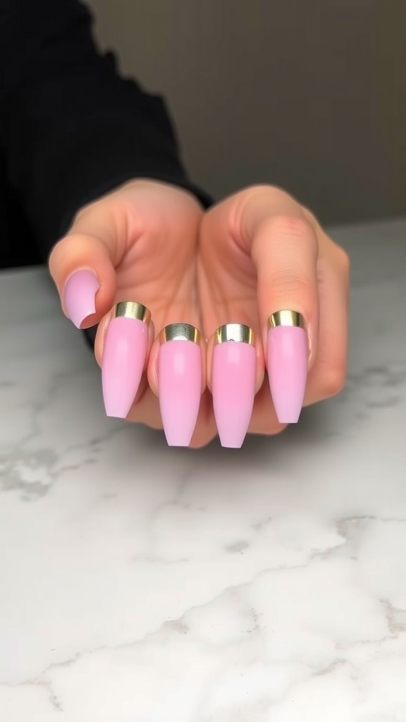 A close-up of short light pink chrome nails with a shiny finish and a gold accent.