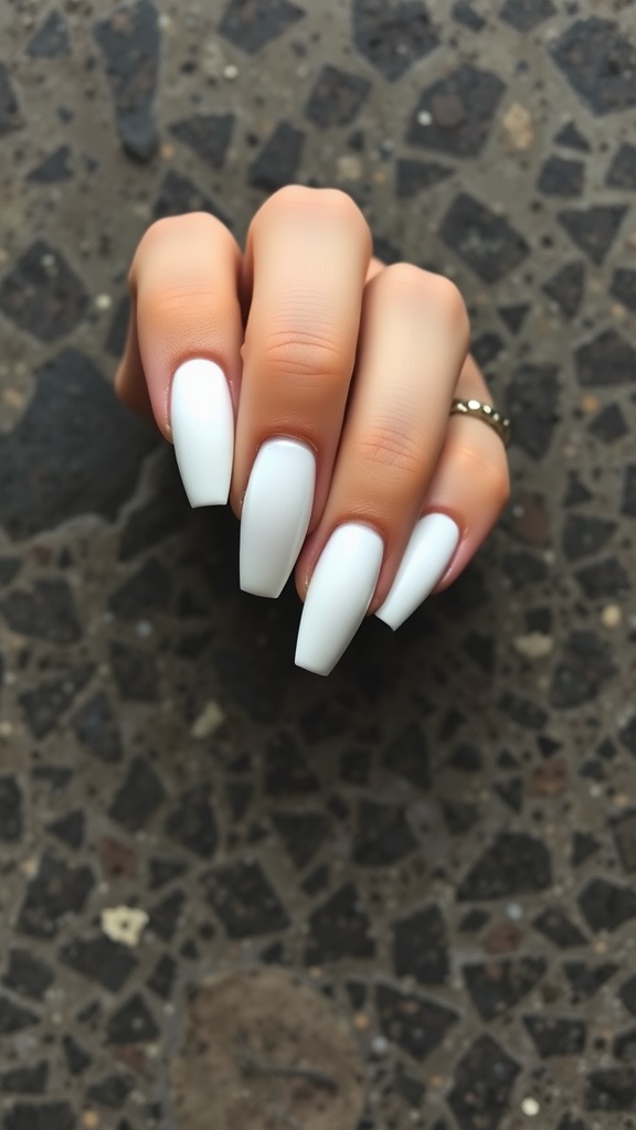 A hand showing off matte white almond nails against a textured background.
