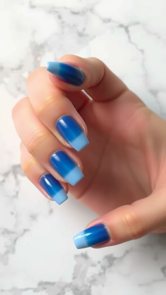 A hand with ombre blue French tip nails, featuring a gradient from dark to light blue.