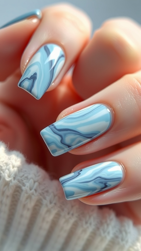 Close-up of ombre light blue marble nail design on well-manicured fingers.