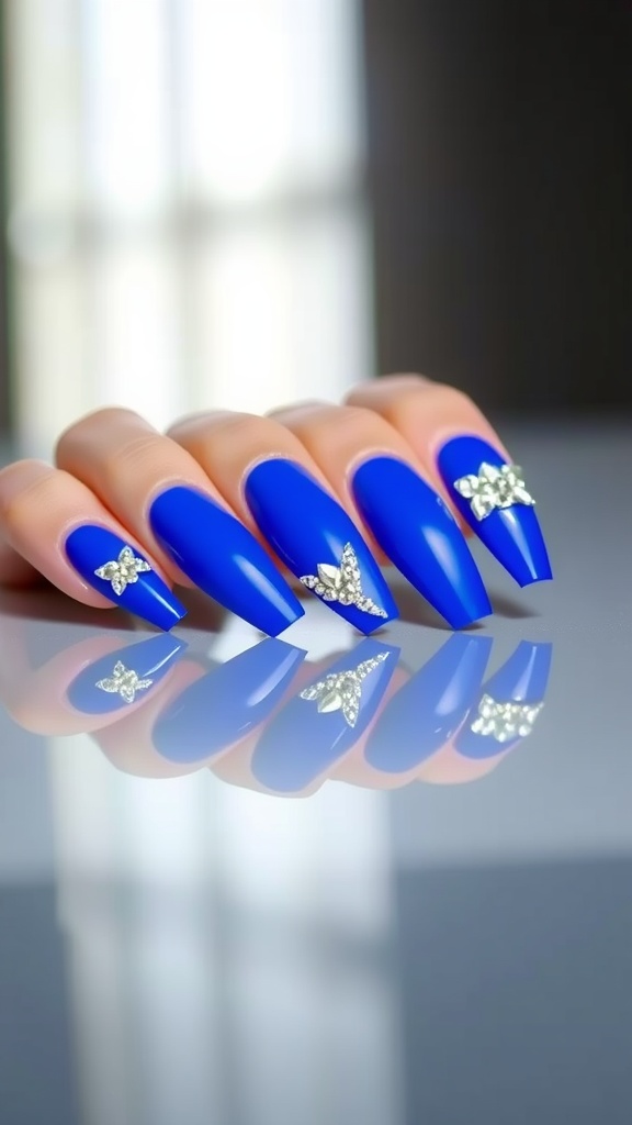 A close-up image of royal blue acrylic nails with crystal accents, showcasing a vibrant and stylish design