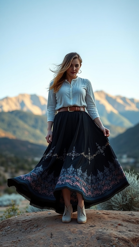 A woman wearing a long embroidered black skirt and a light button-up shirt, standing outdoors with mountains in the background.
