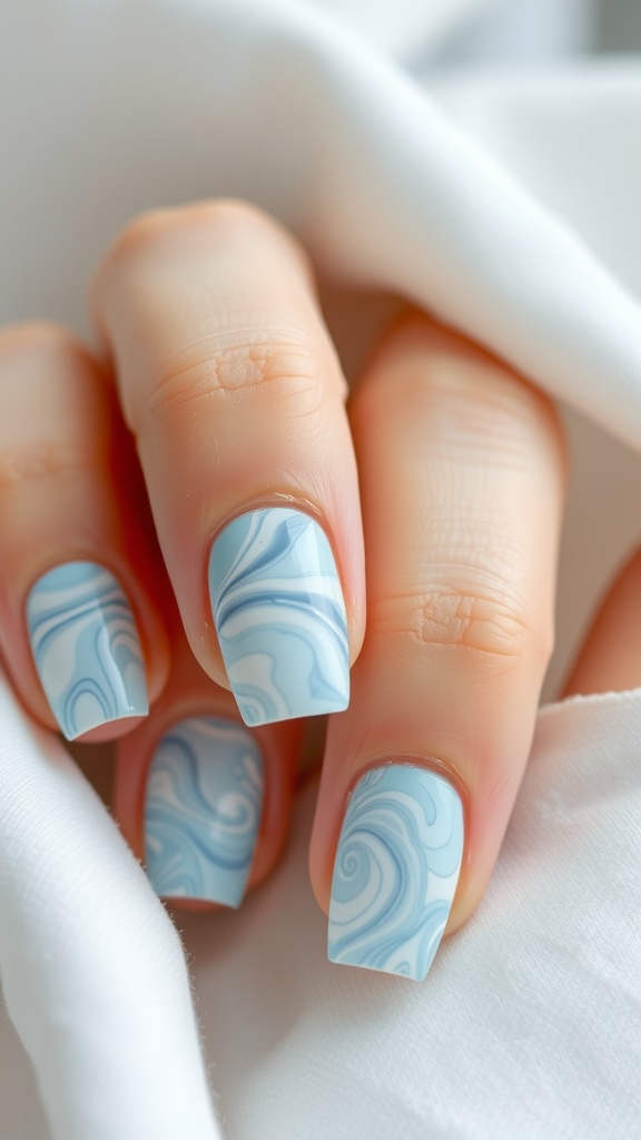 Close-up of light blue marble patterned nails with swirling designs