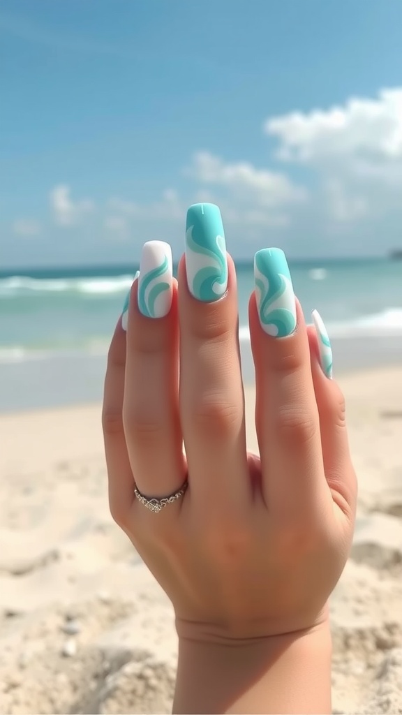 Hand with turquoise and white swirl nail design, beach in background
