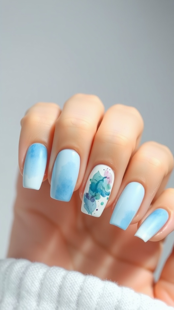 Watercolor light blue nail art with a gradient effect and floral accents on one nail.