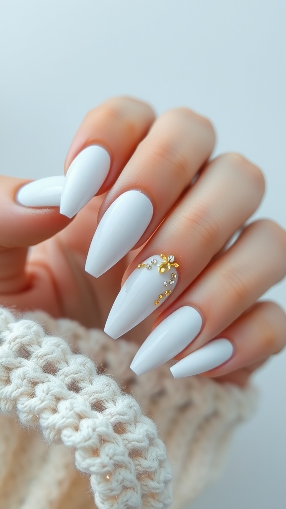 A hand showing white nails with gold accents and rhinestones
