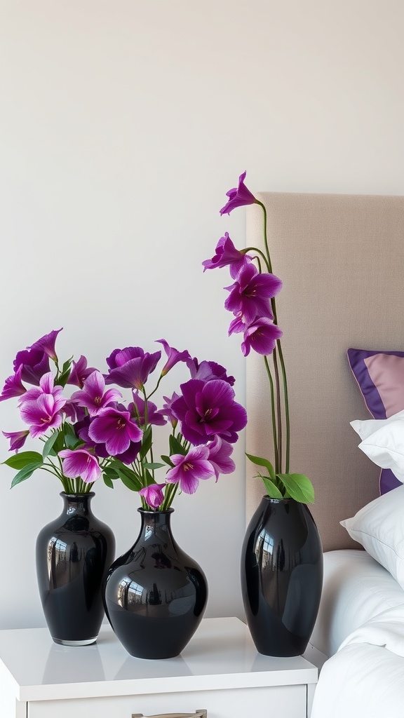 Purple flowers in black vases on a bedside table in a stylish bedroom.